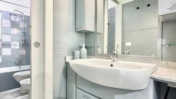 Un bagno moderno con un lavandino ampio, uno specchio e un'area doccia.