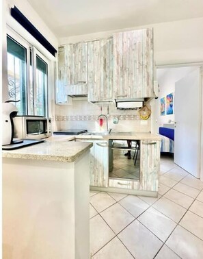Una cucina con forno a microonde, lavandino e mobili in legno.
