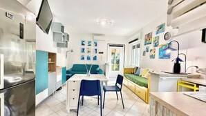 A compact living space with a kitchenette, a dining area, and a sofa. - Hostdomus - Bougainvillea House (Pietra Ligure)
