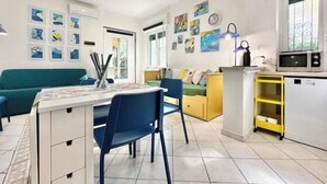 A modern living room with a dining area, a kitchen with a microwave, and a yellow cabinet. - Hostdomus - Bougainvillea House (Pietra Ligure)