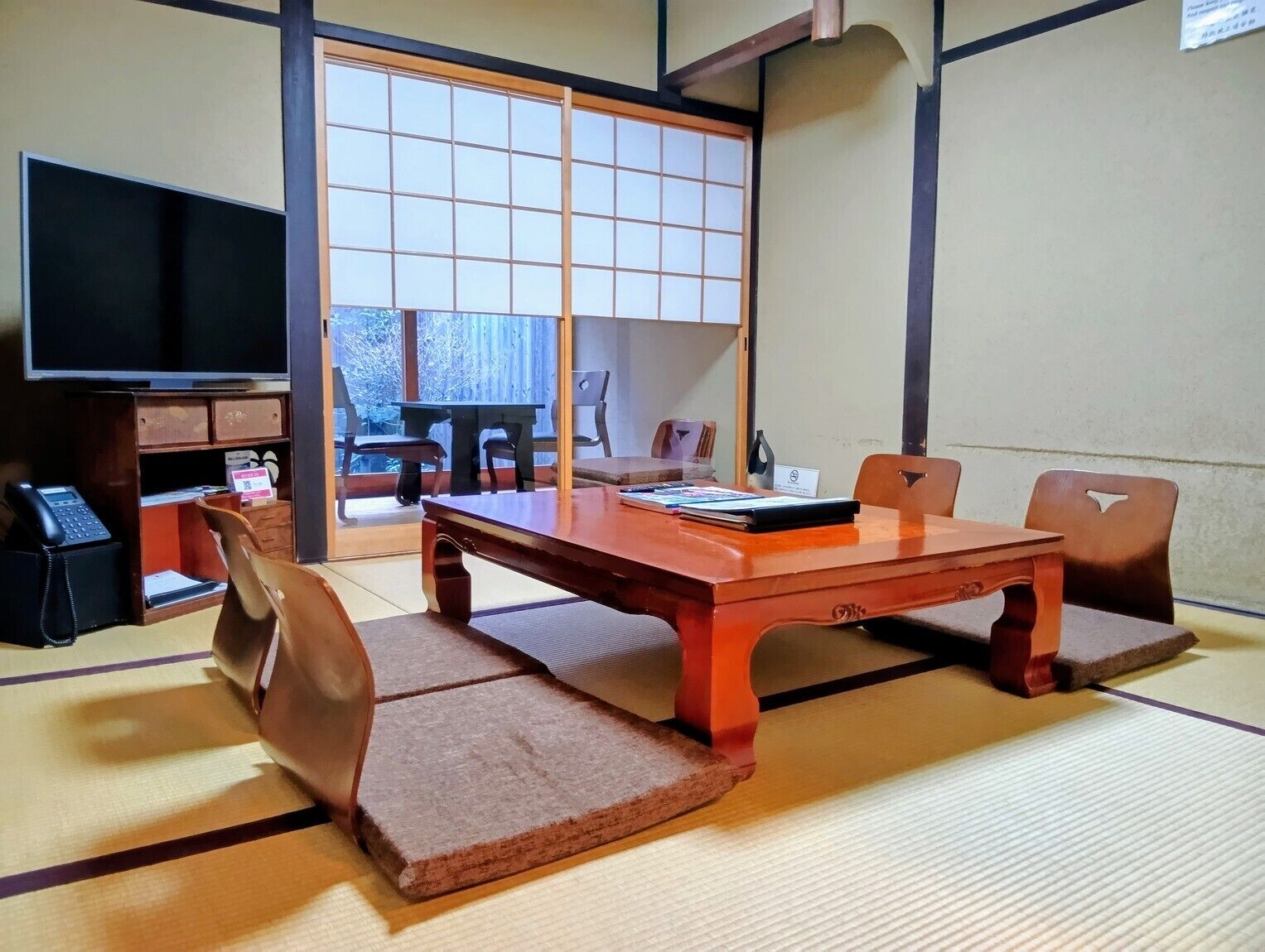 A traditional Japanese room with tatami flooring, a low wooden table, and a sliding door with a grid pattern.