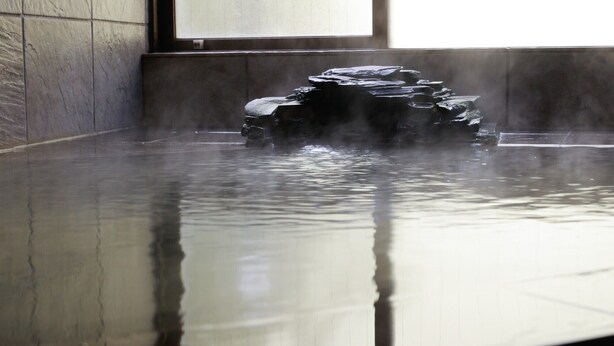 A hot spring with a stone structure in the center, surrounded by tiled walls. - Izu Atagawa Onsen Yurakutei (Higashiizu)