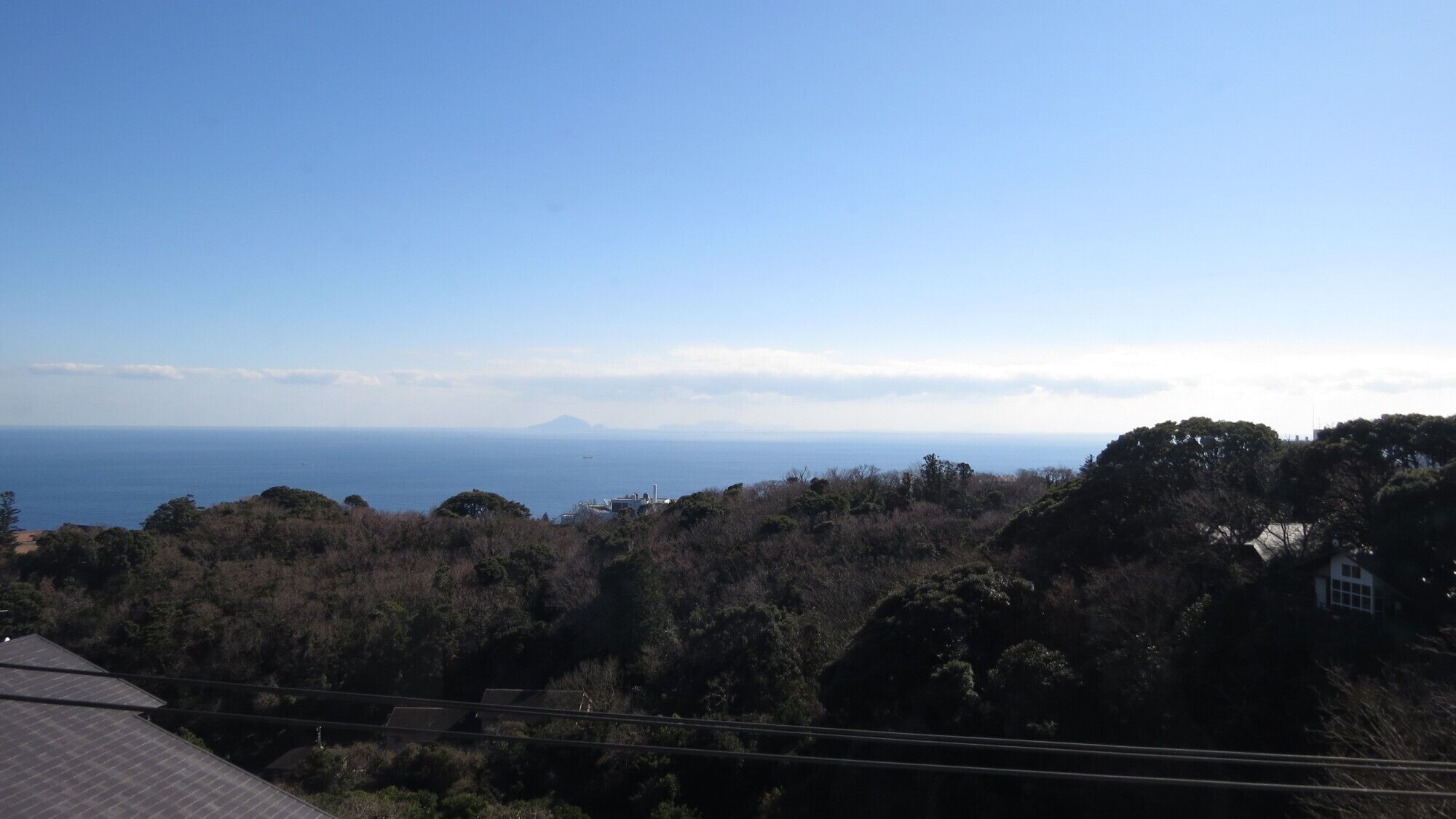 A coastal landscape with a view of the sea and a distant mountain.