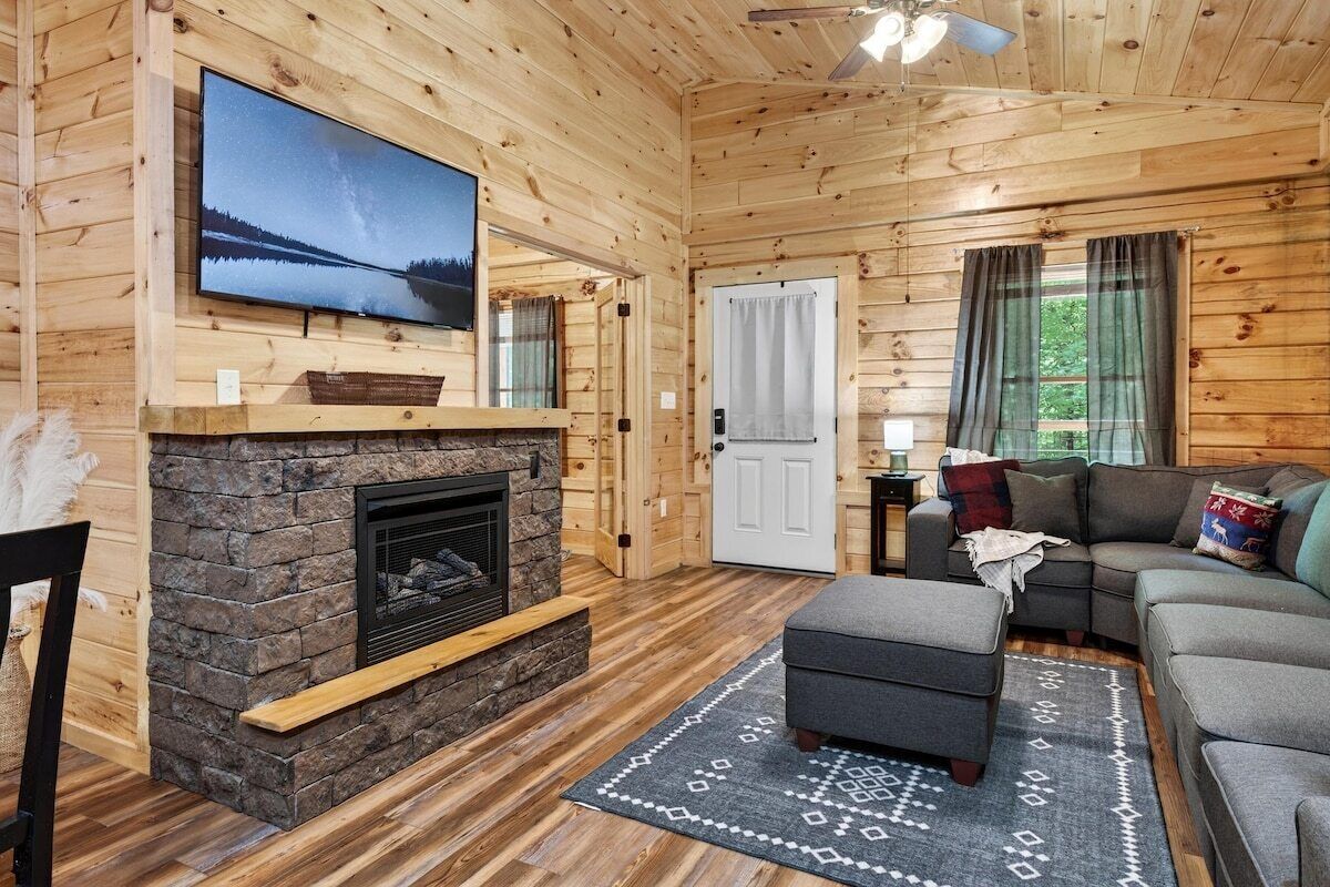 Un intérieur en bois avec une cheminée, un canapé et un téléviseur.