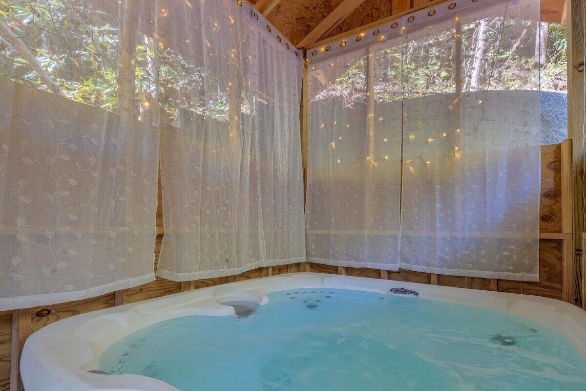 A hot tub with a wooden interior and sheer curtains.