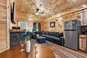 Ein Holzblock-Innenraum mit Essbereich, Wohnzimmer, Küche und Deckenventilator.