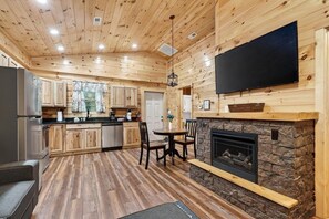 A log cabin interior with a kitchen, dining area, and fireplace. - Gatlinburg Cabin w/ Private Hot Tub & Free Tickets (Gatlinburg)