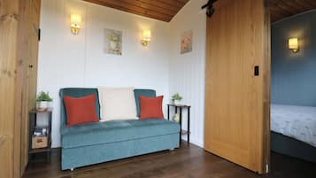 A cozy room with a teal sofa, wooden flooring, and a sliding door leading to another room.