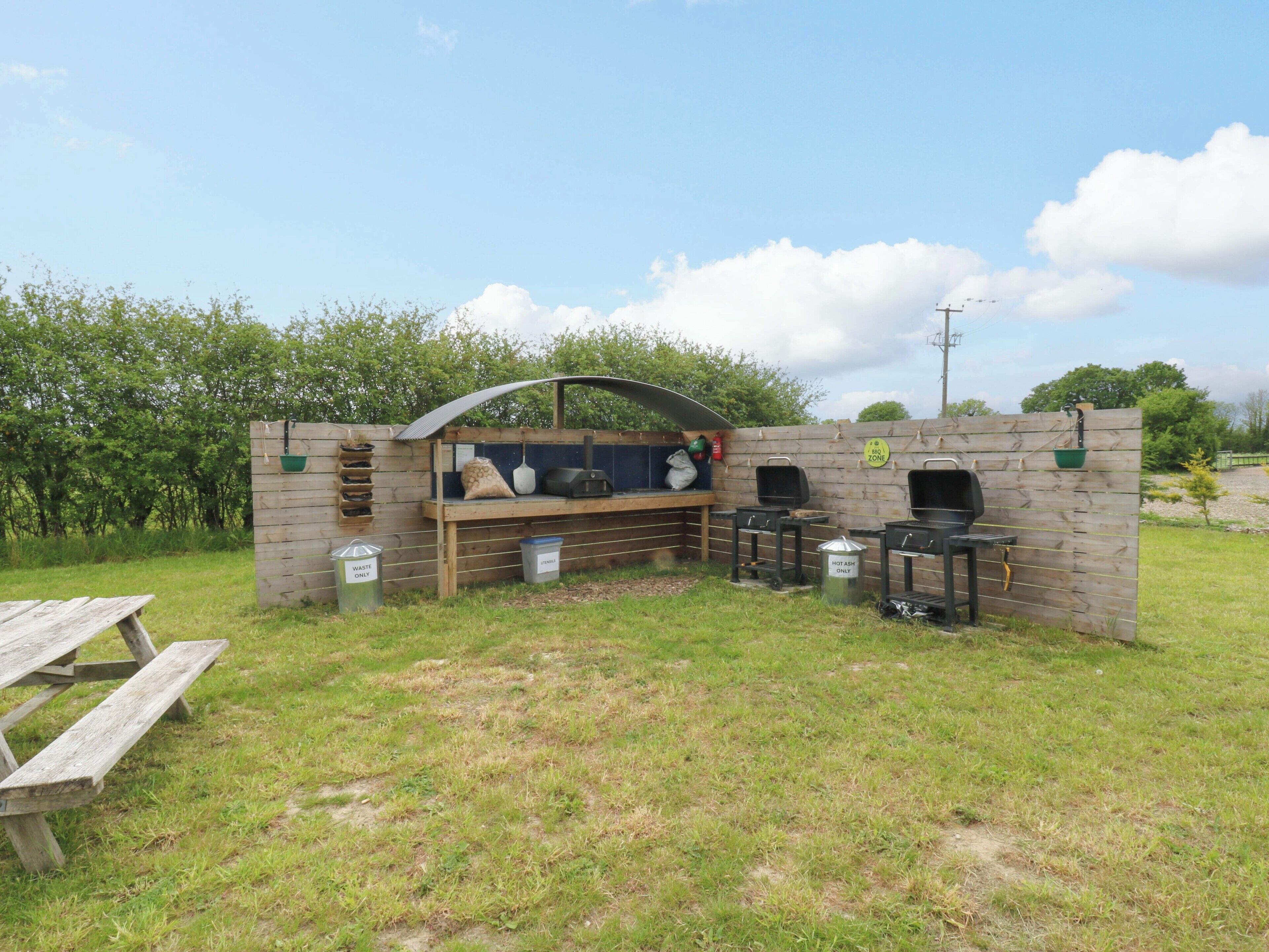 An outdoor barbecue area with a grill, a sink, and a picnic table.
