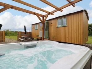 A wooden cabin with a hot tub and a covered patio area.