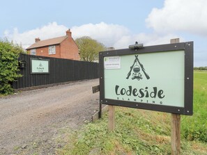 A sign for Lodeside Glamping with a tent and campfire symbol. - The Kestrel (Cambridge)