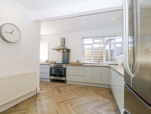 Eine moderne Küche mit eingebautem Backofen, einer Edelstahl-Dunstabzugshaube und einem großen Kühlschrank.