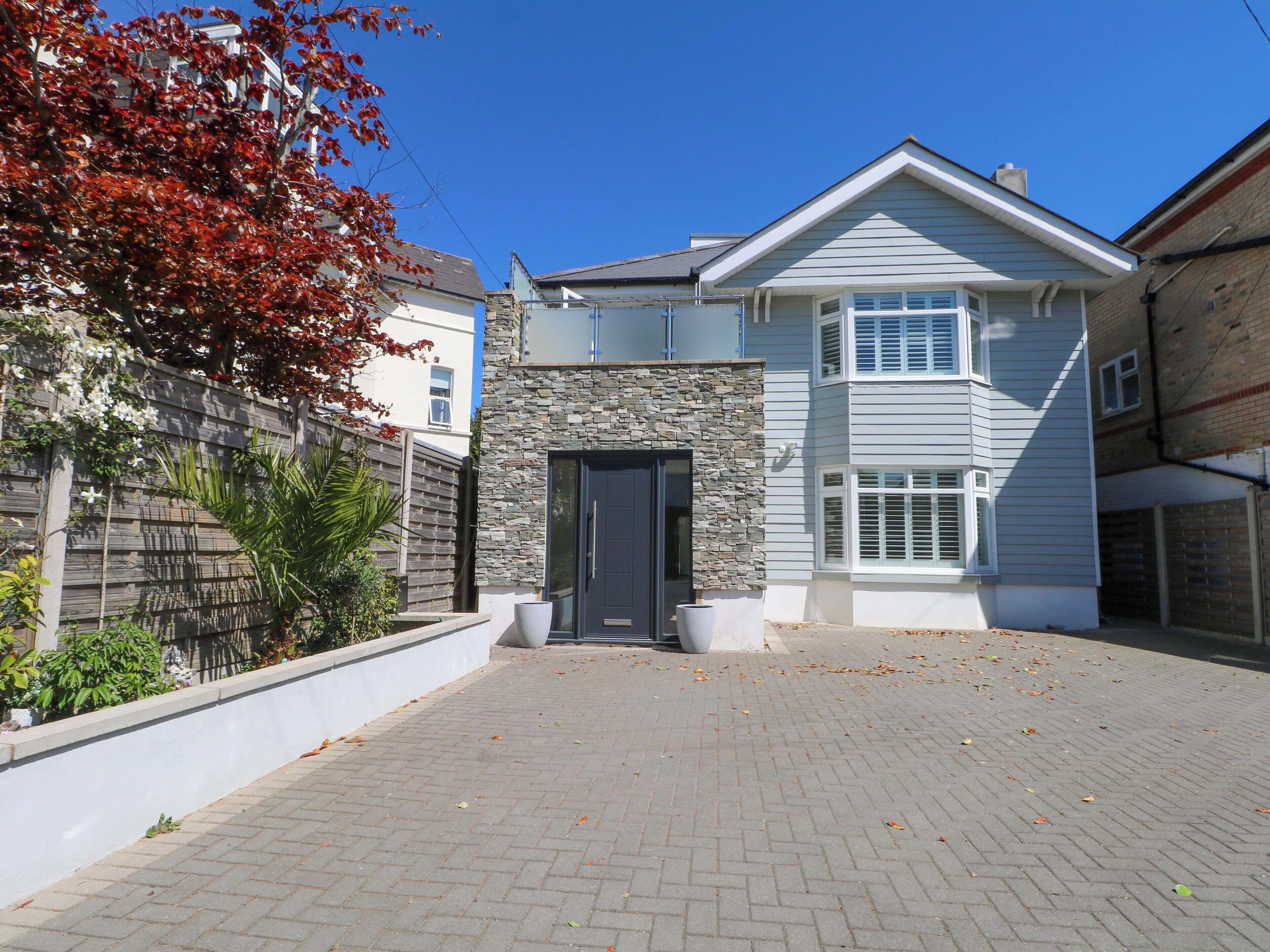 A two-story house with a stone facade, a dark front door, and a paved driveway.
