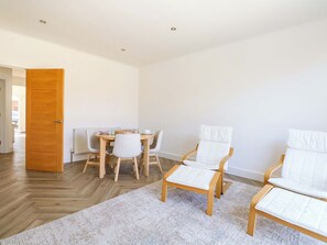 Ein moderner Essbereich mit Holztisch, weißen Stühlen und einem gemusterten Teppich.