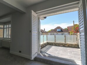 Ein Zimmer mit großem Fenster, einer Steinterrasse und Blick auf eine Wohngegend.