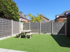 A backyard with a wooden fence, a picnic table, and artificial grass. - Shoreline Retreat (Bournemouth)
