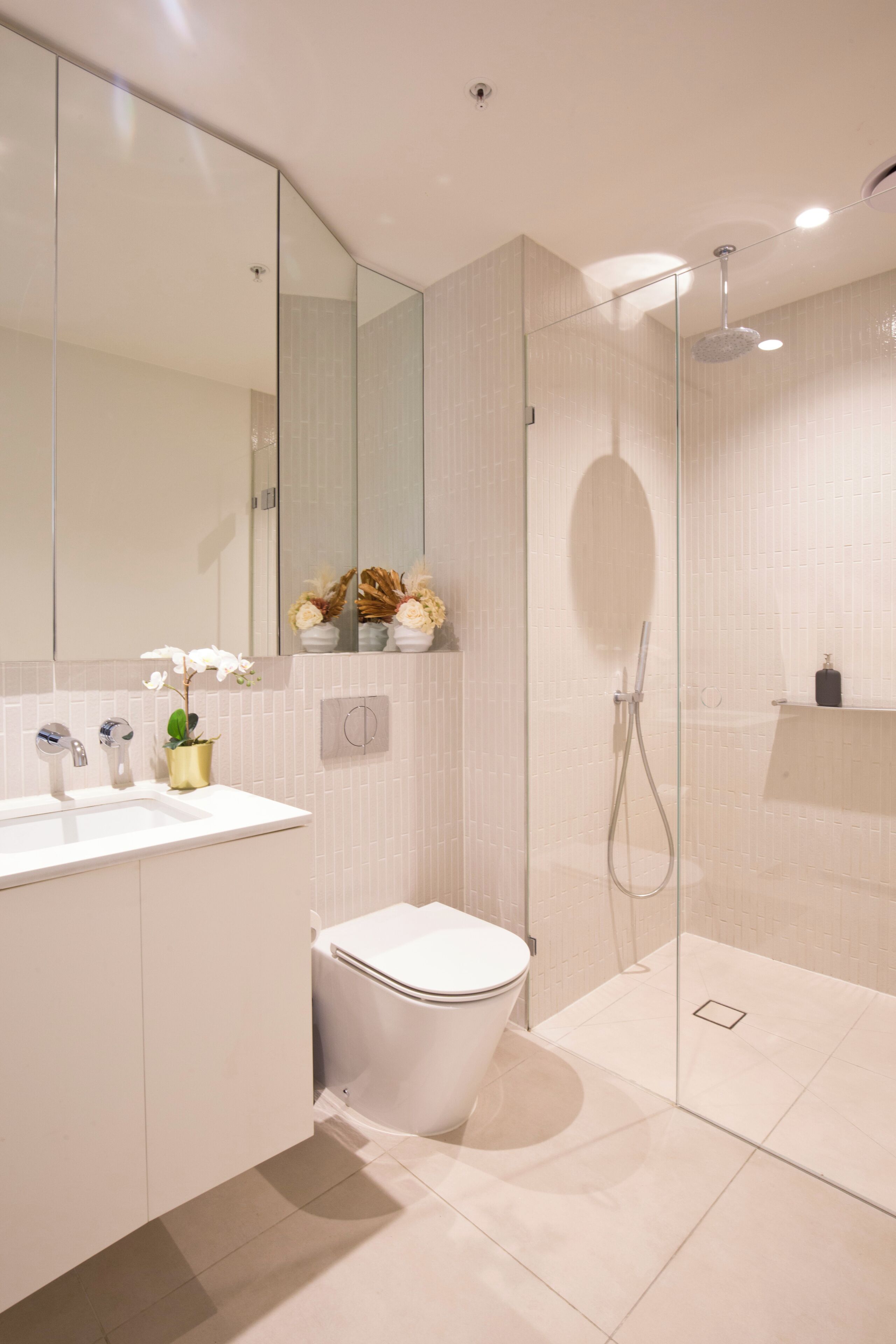 A modern bathroom with a glass-enclosed shower, a white sink, and a toilet.