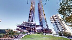 A modern building with a unique curved facade, surrounded by a well-maintained lawn and a few trees. - Melbourne Square Southbank (Southbank)