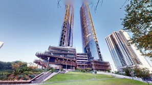A modern building with a unique curved facade, surrounded by a well-maintained lawn and a few trees. - Melbourne Square Southbank (Southbank)