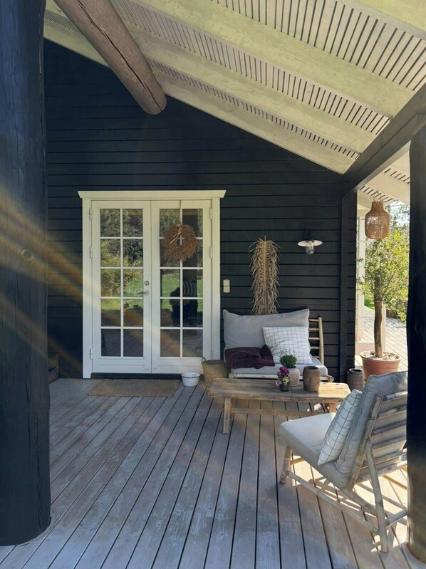 A covered porch with a wooden bench, a white door, and a hanging wreath. - Summer house with soul and family roots in Rørvig (Nykøbing Sjælland)