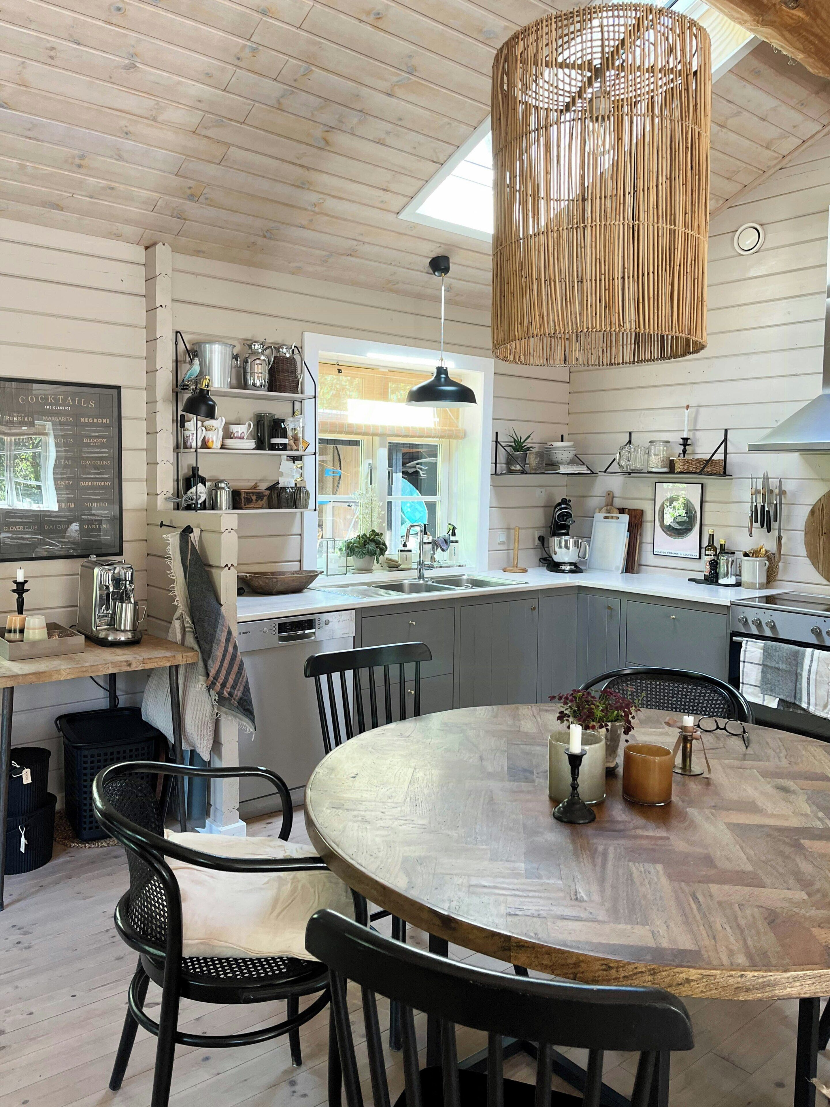 A kitchen with wooden cabinets, a round dining table, and a hanging light fixture.