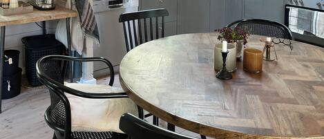 A kitchen with wooden cabinets, a round dining table, and a hanging light fixture.