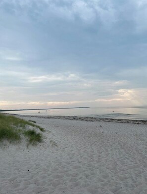 A beach with sand and grass, a calm sea, and a cloudy sky. - Summer house with soul and family roots in Rørvig (Nykøbing Sjælland)
