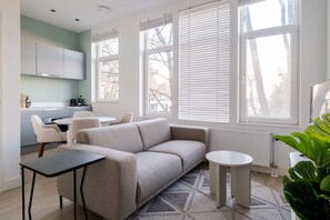 A modern living room with a sofa, a small table, and a dining area with chairs. - Modern One Bedroom Apartment - Rotterdam West (Rotterdam)