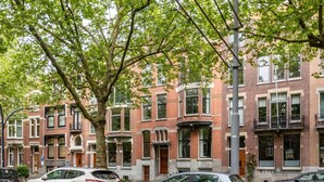 A row of brick townhouses with multiple stories, large windows, and a tree-lined street. - Bright Ground-floor Apartment With Garden (Rotterdam)