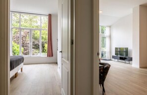 Ein Zimmer mit einem Bett, einem Fernseher und einem großen Fenster.
