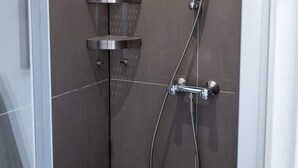 Eine Duschkabine mit Handbrause und am Wand montiertem Wasserhahn.