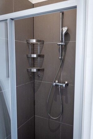A shower enclosure with a handheld showerhead and a wall-mounted faucet. - Prachtige Studio in Hartje Rotterdam (Rotterdam)