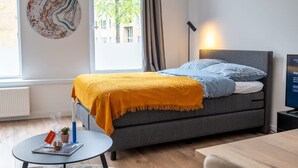 Ein modernes Schlafzimmer mit einem Bett, einem kleinen Tisch, einer Lampe und einem Wandbild.