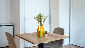 Een eettafel met een bloevas, een kleine cactus in pot en een stoel.