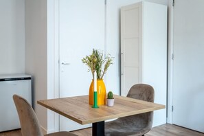 Ein Esstisch mit einer Pflanzenvase, einem kleinen Kakteentopf und einem Stuhl.