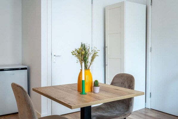 A dining table with a vase of plants, a small potted cactus, and a chair. - Prachtige Studio in Hartje Rotterdam (Rotterdam)