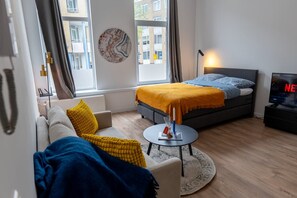 A modern bedroom with a bed, a sofa, a coffee table, and a TV. - Prachtige Studio in Hartje Rotterdam (Rotterdam)