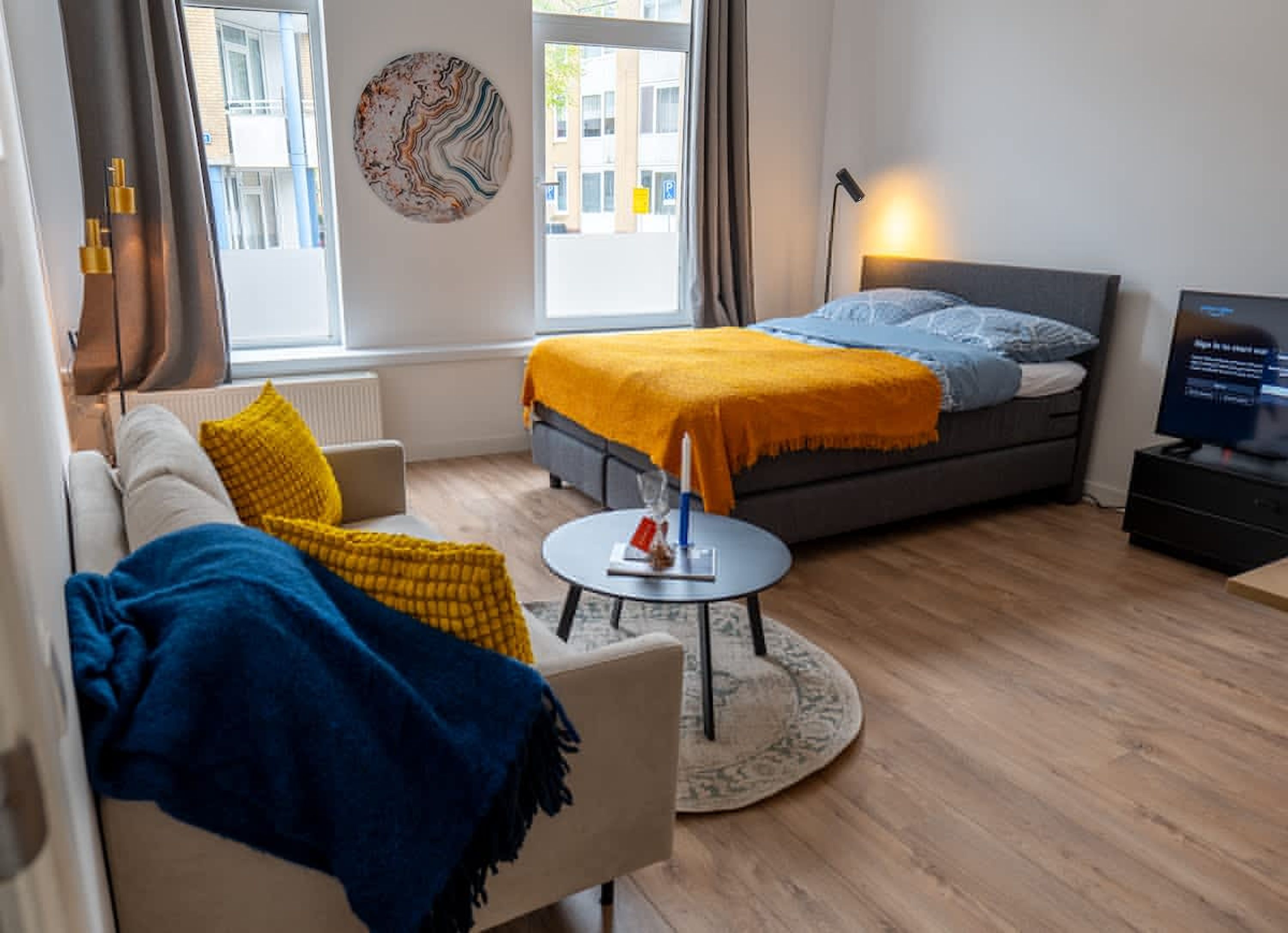 Een moderne hotelkamer met een bed, een bank en een kleine tafel.