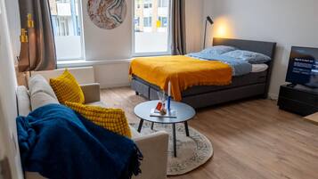 Een moderne hotelkamer met een bed, een bank en een kleine tafel.