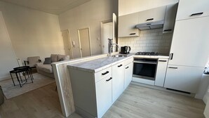 Uma cozinha moderna com armários brancos, uma ilha central, um fogão e uma pia.