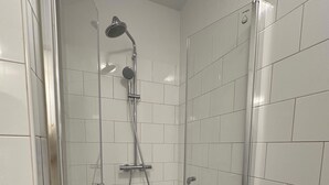 Um chuveiro pequeno e fechado, com azulejos brancos e uma porta de vidro.