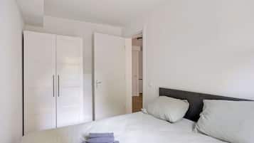 Un dormitorio con cama, dos almohadas, una mesita de noche y un armario.