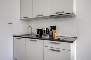 Eine moderne Küche mit schwarzem Arbeitsplatz, Edelstahlgeräten und weißen Schränken.