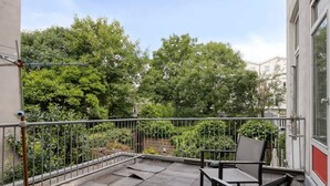 A balcony with a metal railing, a chair, and a table. - Bright Apartment With Private Terrace (Rotterdam)