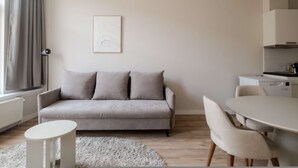 Una sala de estar moderna con un sofá gris, una mesa blanca y un comedor.