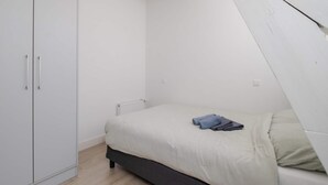 Et soveværelse med seng, skab og radiator.