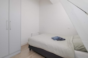 Ein Schlafzimmer mit einem Bett, einem Kleiderschrank und einem Heizkörper.