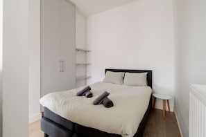 A bedroom with a bed, a wardrobe, a small table, and a radiator. - Cosy City Apartment in Rotterdam West (Rotterdam)