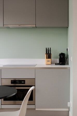 A kitchen with a built-in oven, a coffee machine, and a knife block on the counter. - Cosy City Apartment in Rotterdam West (Rotterdam)