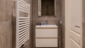 A narrow bathroom with a white vanity, a towel rack, and a mirror. - Cosy City Apartment in Rotterdam West (Rotterdam)
